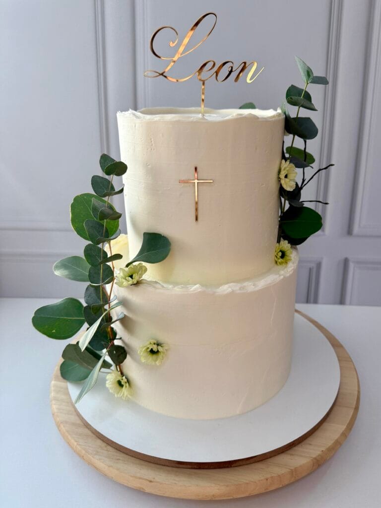 Elegantná dvojposchodová torta vhodná na prvé sväté prímanie alebo birmovku zdobená minimalistickým krížikom a zelenými lístkami od LE BON - Považská Bystrica.