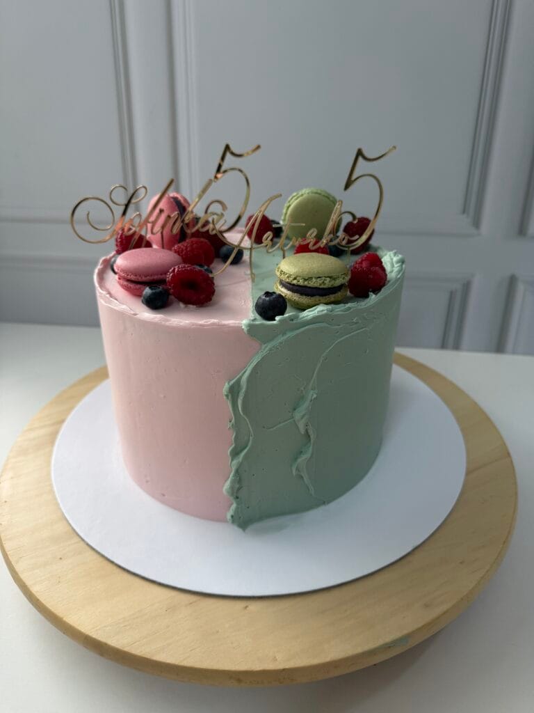 Elegantná dvojfarebná jednoposchodová krémová torta zdobená lesným ovocím a makrónkami.